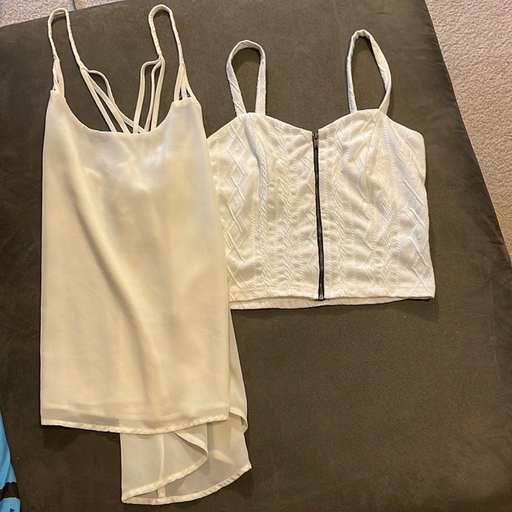 2 tanks: left tank beige with strap detailing. Right tank white with front zip